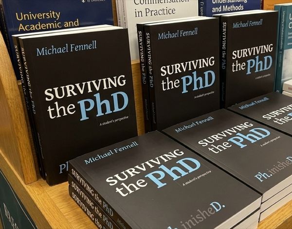 Academic hardback with reading glasses, highlighter and research notes on an oak desk