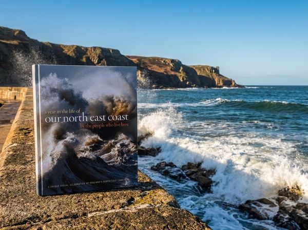 Local history book with archive photographs and vintage map on oak table